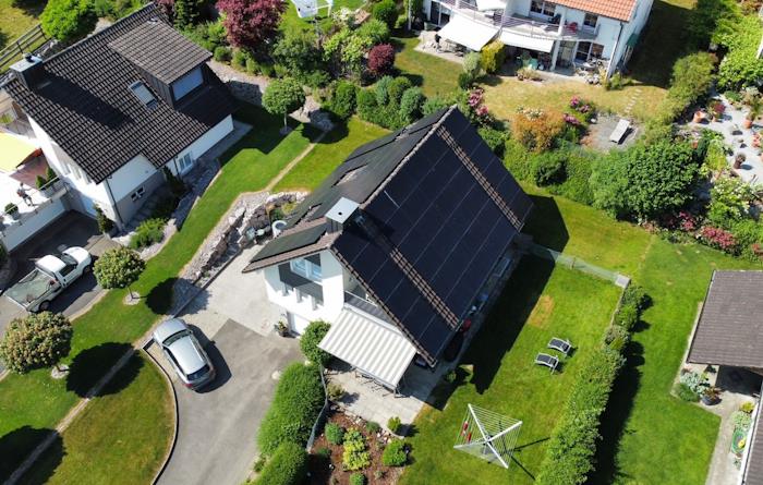 Haus mit Solarpanels auf dem Dach und grünem Garten